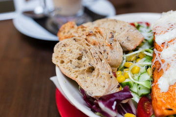 Dinner at restaurant. Chopped loaf. Close-up salad with grilled chicken, corn, tomato and cucumber