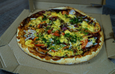  Pizza with mushrooms, sausage cheese and herbs, on the table in a cortoon package.       