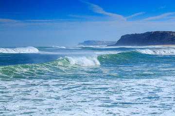 A huge waves on the ocean coast in a shine bright light  at sunny day. Wonderful romantic seascape of ocean coastline.
