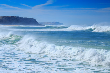 A huge waves on the ocean coast in a shine bright light  at sunny day. Wonderful romantic seascape of ocean coastline.