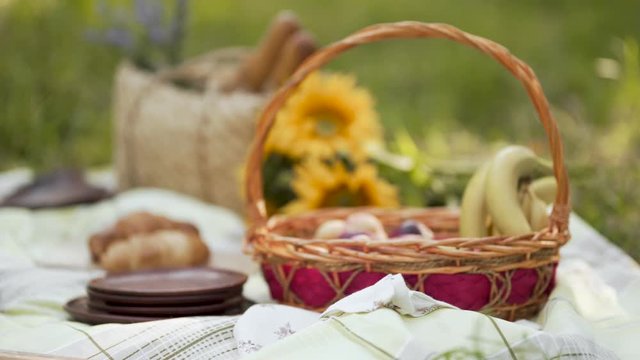 A wicker picnic basket set up with fruit on a green grassy field