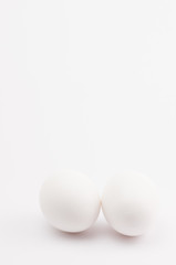 two white eggs on a white surface - nature shapes backdrop