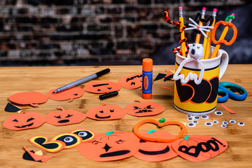 Construction paper jack-o-lanterns,  being made with other crafts and tools tools for crafting and scrapbooking.  Room for Copywriting on the background.