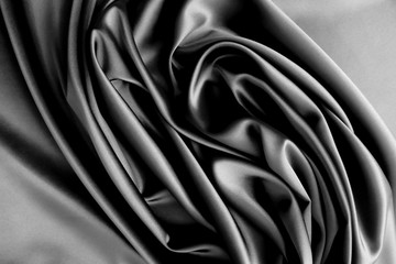 Smooth elegant black or dark grey silver silk or satin luxury cloth fabric texture, abstract background design.