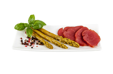 Green asparagus and pork sirloin on a plate on a white background.