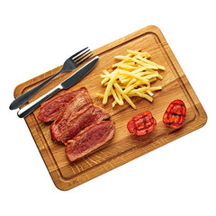 Steak with French fries and grilled cherry tomatoes on a cutting board. Classic meat meal isolated on white background. Top view, directly above flat lay shot.