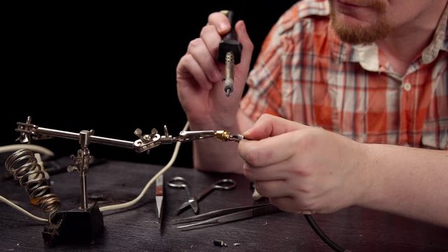 Process of replacing cable for audio cinch connector.Muscled blond electrician solder wire with rosin soldering iron to RCA jack plug.