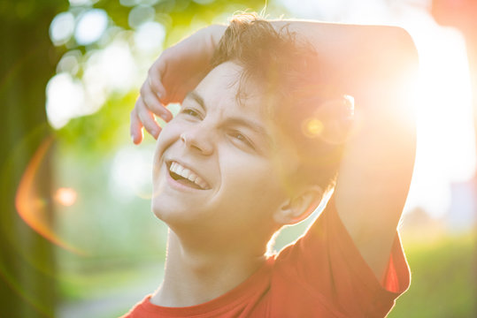 Close up portrait of teenage boy with sun rays. Happy smiling teen at summer park in flare sunshine. Handsome child looking away during sunset. - Powered by Adobe