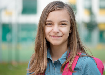 Portrait of beautiful student teenager schoolchild go to school with backpack. Cute child - teen girl with bag against the background of school. Back to school concept.