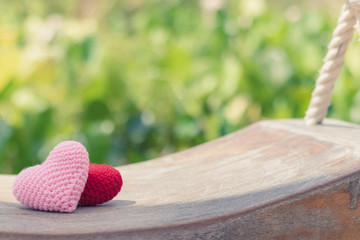 Red and pink hearts on wooden swing with beautiful blurred background