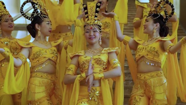 Group of beautiful asian women standing and dancing with hands in a traditional thai yellow dresses and hats