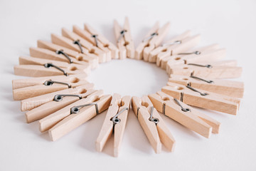 Group of wooden clothespins arranged in a circle isolated on white background. Copy space