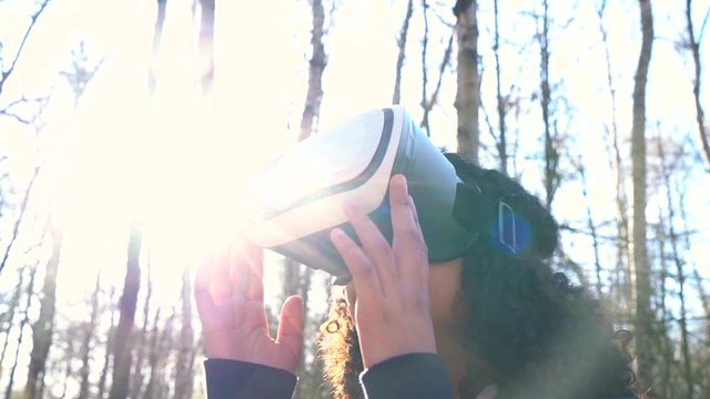 4K video clip of beautiful mixed race African American girl teenager female young woman using virtual reality VR headset in a forest woodland environment - Powered by Adobe