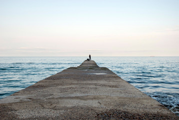 A fisherman on the sea breakwater with fishing rod