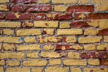 old damaged white, beige, red brick wall with yellow spots of paint close-up. rough surface texture