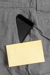 Smartphone device inside formal work trousers front pocket near note paper