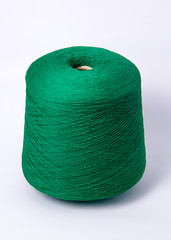 Green bobbin of yarn on a white background.Textile reel on isolated white background.