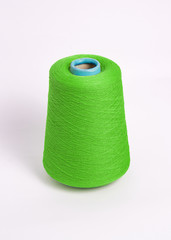 Green bobbin of yarn on a white background.Textile reel on isolated white background.