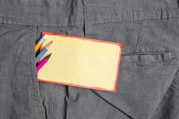 Writing equipment and yellow note paper inside pocket of man work trousers