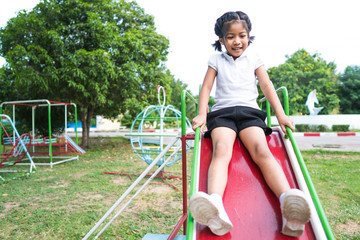 Healthy little kids are playing in the backyard, happy with the swings, rocking horses, slide...