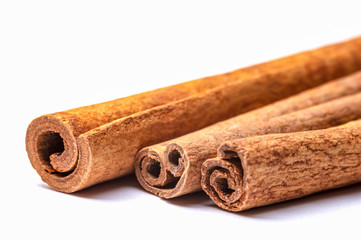 Three cinnamon sticks on a white background. Close-up photo