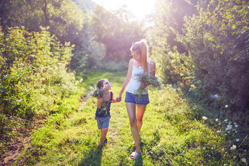 Naklejka premium Mother and son picking flowers / herbs in nature.