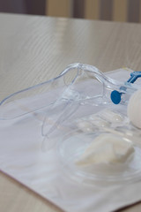 Plastic vaginal speculum. Pills and other tools in the background.