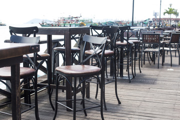 Beach cafe with wooden tables and chairs placed at the sea waterfront