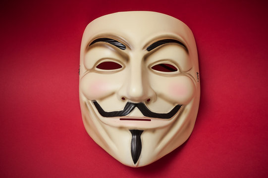 Mulhouse - France - 17 January 2019 - Vendetta mask on red paper background . This mask is a well-known symbol for the online hacktivist group Anonymous