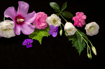 Fototapeta na wymiar Black background with purple hibiscus heads, crimson oleander on leaves, white Lisianthus with buds and small violets