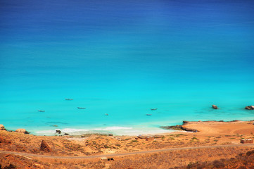 A view of the emerald water of the Indian Ocean and boats in the water. Wild coast of Socotra island.