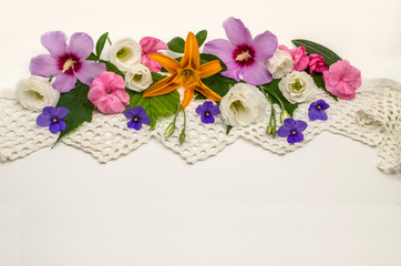 White background with openwork border,located at the top, covered with heads of flowers of purple hibiscus, white Lisianthus, raspberry oleander and violets on the leaves