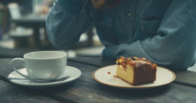 Young woman drinking coffee and eating cake