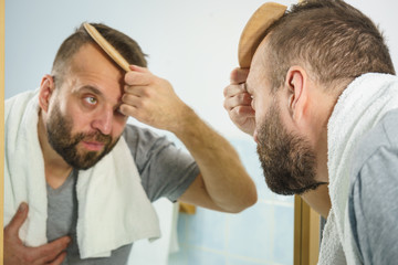 Fototapeta premium Man using comb in bathroom