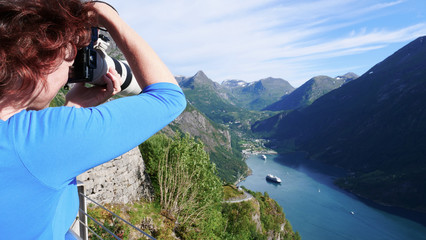 Tourist taking photo of fjord landscape, Norway