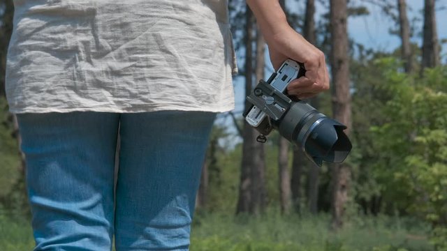 Woman photographer walks with a camera in hands.