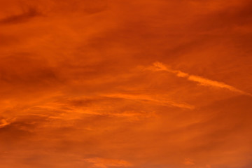 Fototapeta na wymiar Sunset sky background of a full covering of light clouds glowing an orange color