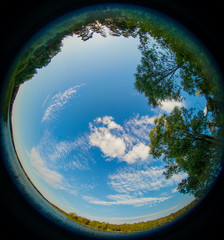 A fisheye view of Russian nature, blue lake and green grass with sunny sky