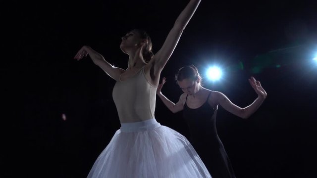 Tender ballerinas in white and black tutu spinning in dance. Close up, slow motion.