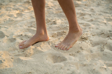 Fototapeta na wymiar bare male feet walk on the sandy beach, healthy yoga practice concept