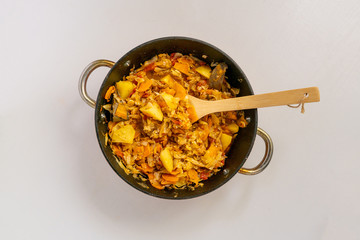 top view of vegetable stew  mix in cauldron on a color surface with a wooden stick