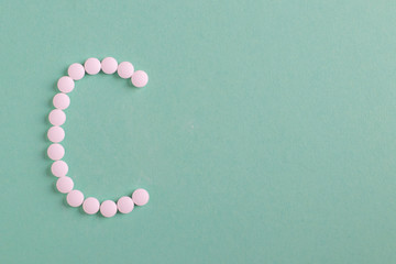 Vitamin C , letter C made from pills on turquoise background