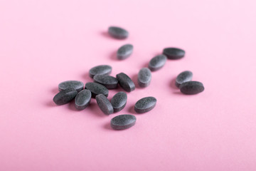 Spirulina tablets, chlorophyll on a pink background