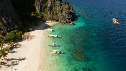 Obraz premium aerial view island with tropical sandy beach and palm trees. Malajon Island, Philippines, Palawan. tourist boats on coast tropical island. Summer and travel vacation concept. beach and blue clear sea