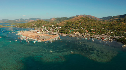 aerial view City Quay with boat dock and public market Coron town, tourist destination in the Philippines. Pier and promenade with boats on Busuanga island. Wooden boats waiting at pier. Seascape with