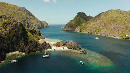 Tropical landscape bay with beach and clear blue water surrounded by cliffs, aerial drone. El nido, Philippines, Palawan. Seascape with tropical rocky islands, ocean blue water. Summer and travel