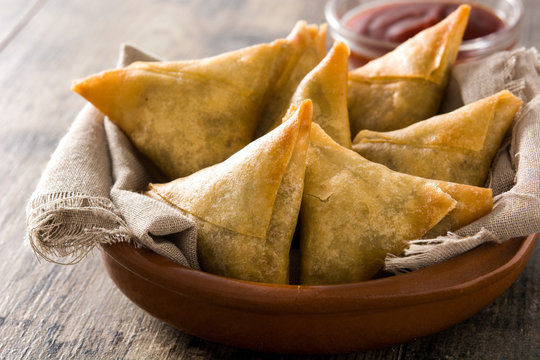 Samsa or samosas with meat and vegetables in bowl on wooden table. Traditional Indian food