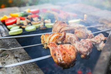 Vegetables and meat on grill. Pepper, tomatoes, mushrooms and zucchini squash. Chicken on open fire. Summer barbecue party. Healthy natural food.