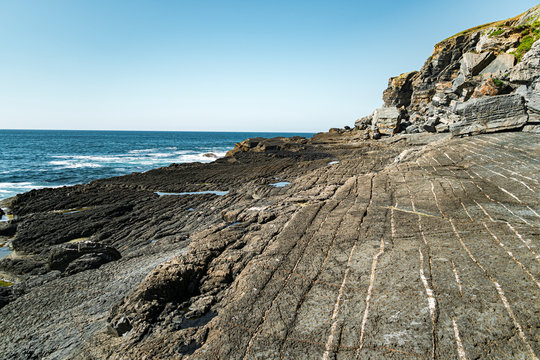 Rocky clifss with textured ground and white lines close to sea in Asturian Coast, Spain
