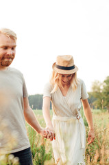 Handsome guy and blonde girl walking on the field on a beautiful warm sunset. gently, standing in the sun. golden hour